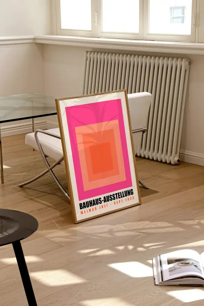 A framed bauhaus geometric canvas print with concentric pink and orange squares and black text for home decor