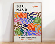 A vibrant bauhaus geometric canvas print in black and orange framed in light wood for modern home decor