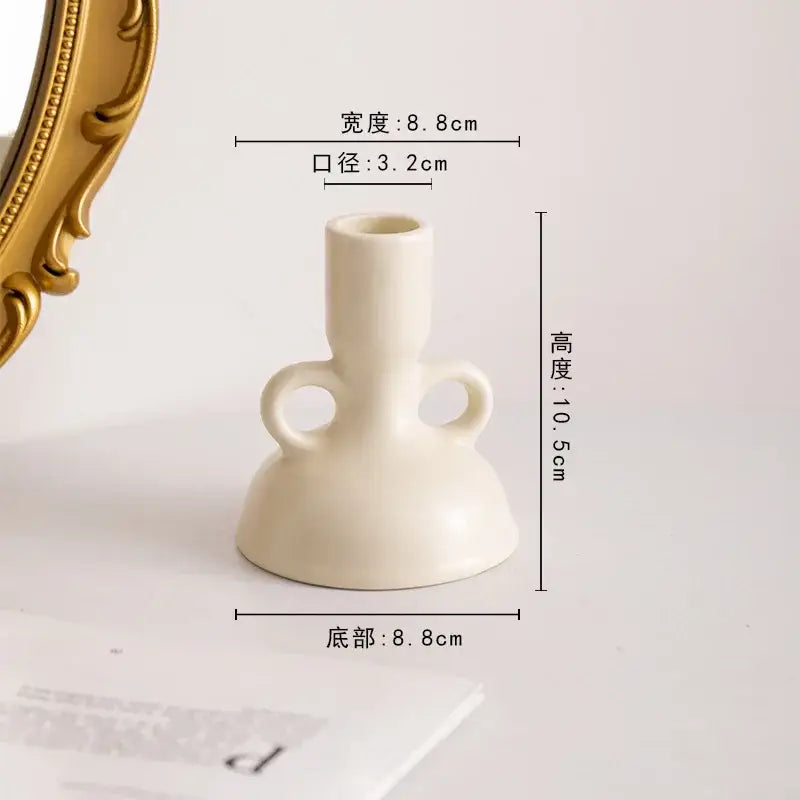 Cream-colored geometric ceramic candle holder with two loop handles and flared base for living room decorbites decor