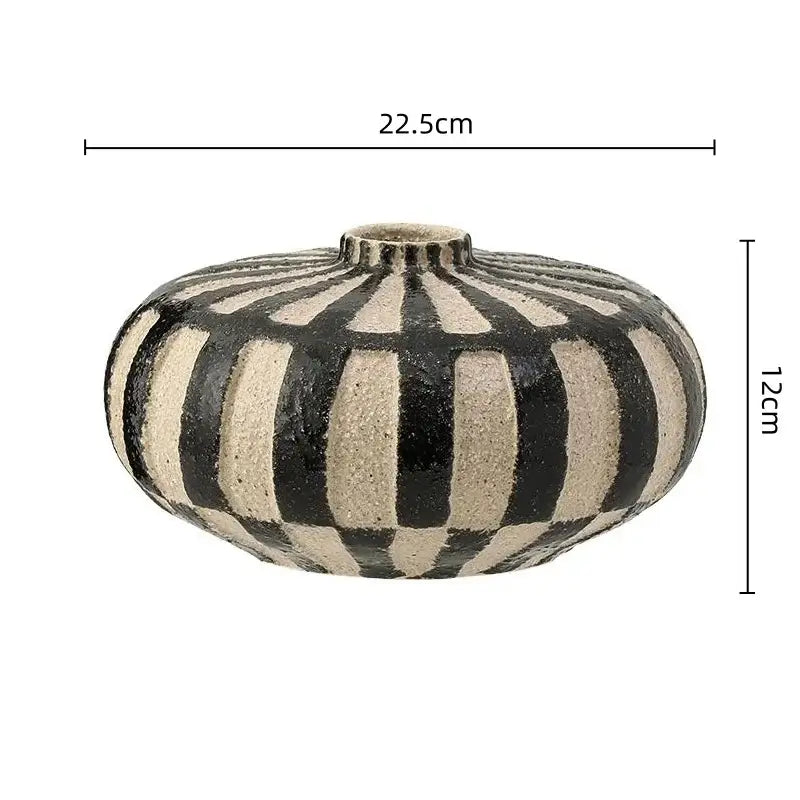 A round geometric check ceramic vase with bold black and beige vertical stripes and a textured surface for living room decor