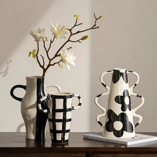 A white ceramic vase with black geometric check pattern and sculpted wavy handles for living room decor