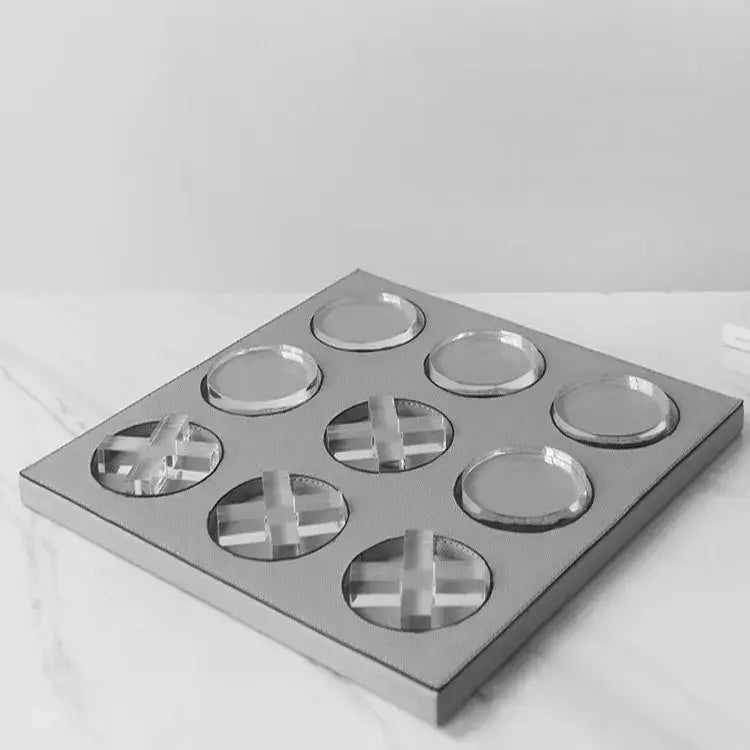 Silver metallic tray with nine circular recesses three containing cross-shaped crystal inserts for geometric checkerboard home decor