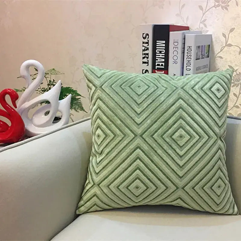 A soft mint green geometric chenille flocking cushion cover on a light gray sofa for living room decor by decorbites