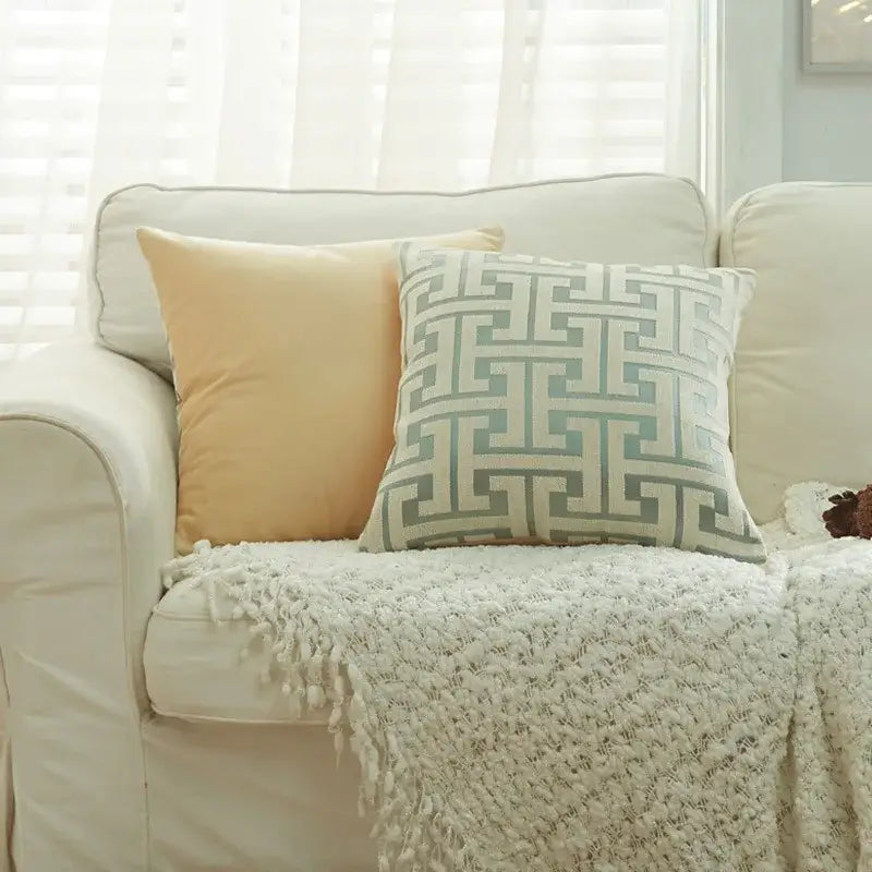A square decorbites geometric chenille throw pillowcase in beige and light blue with a gray maze pattern on a cream couch