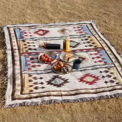 A cream-colored decorbites geometric cotton knitted sofa blanket with red blue and brown patterns and fringed edges