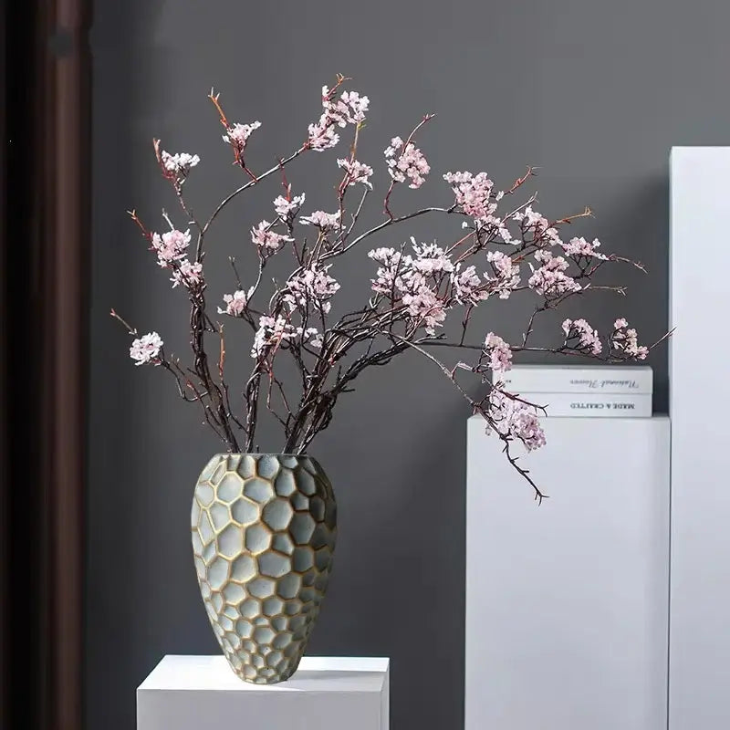 Light gray ceramic vase with geometric diamond check honeycomb pattern holding pink cherry blossom branches for decor