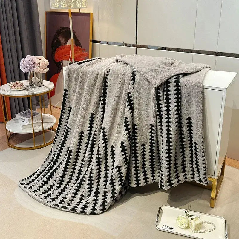 A cozy gray and black geometric double layer lamb fleece blanket with plush textured throw for bedroom use