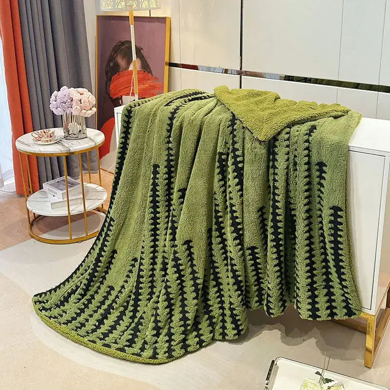 A plush olive green geometric double layer lamb fleece blanket with a textured black pattern draped over a white cabinet