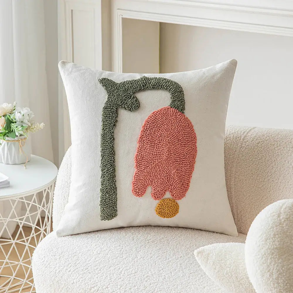 Cream-colored cushion cover with geometric embroidery featuring textured dusty rose and olive green floral yarn design