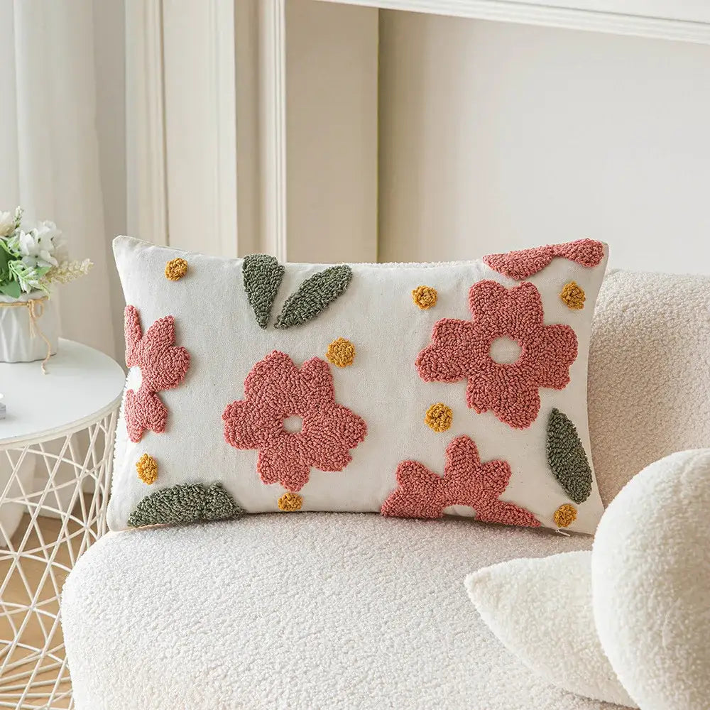 A cozy white cushion cover with raised pink and green floral appliqués featuring geometric embroidery decorbites accents