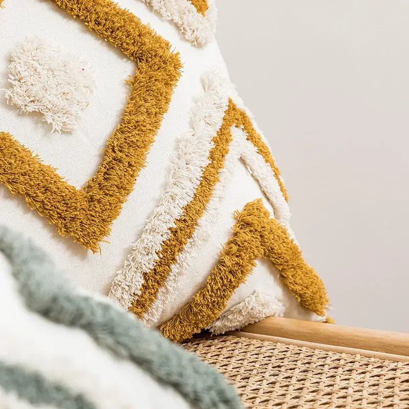 A cozy white and mustard-yellow cushion cover with decorbites geometric embroidery and fringed boho patterns