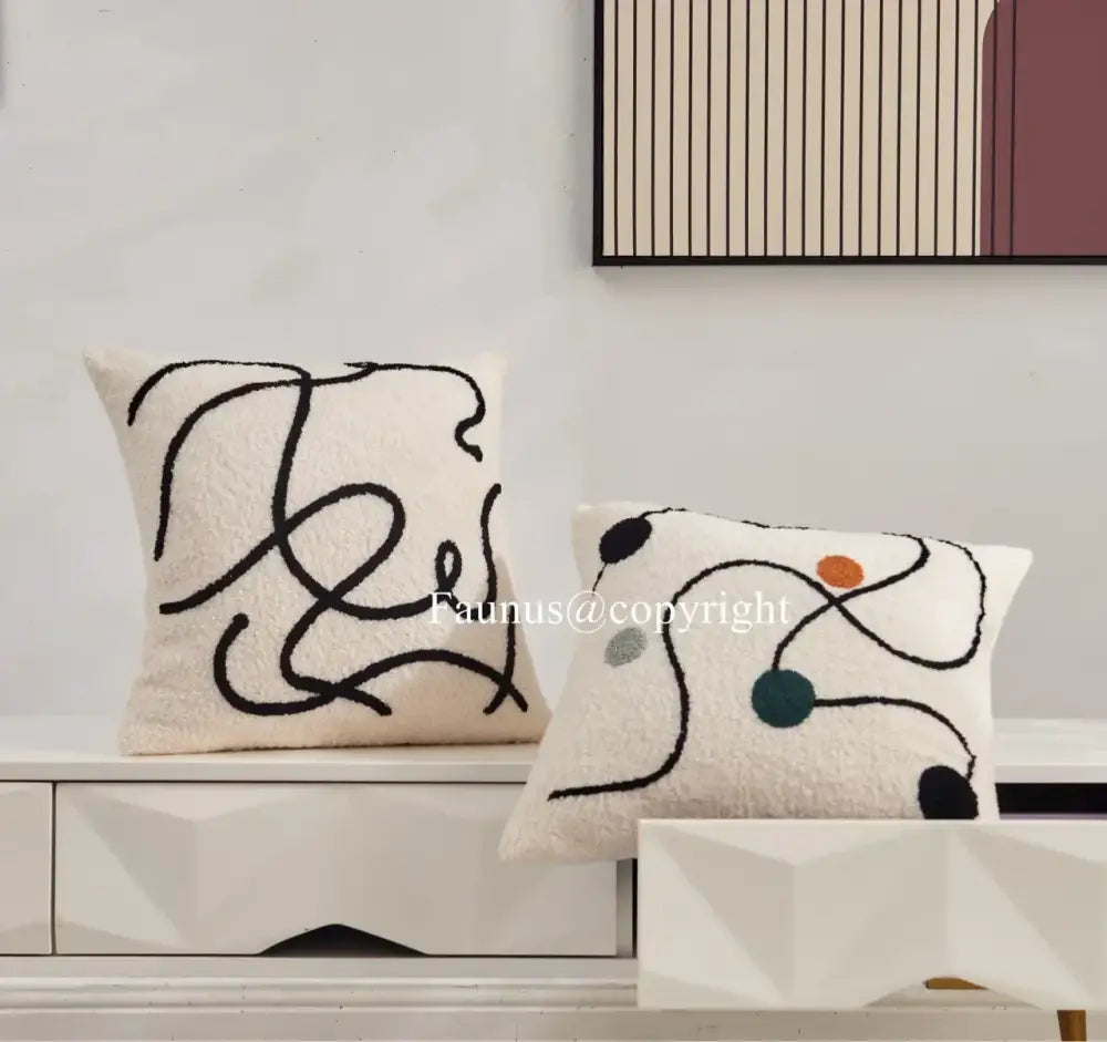 Cream cushion covers with geometric embroidery featuring abstract black line art and colorful circular accents by decorbites