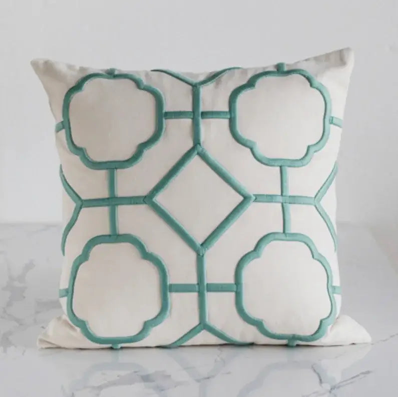 A cream cushion cover with teal scalloped quatrefoil geometric embroidery crafted from soft fabric for living room decor
