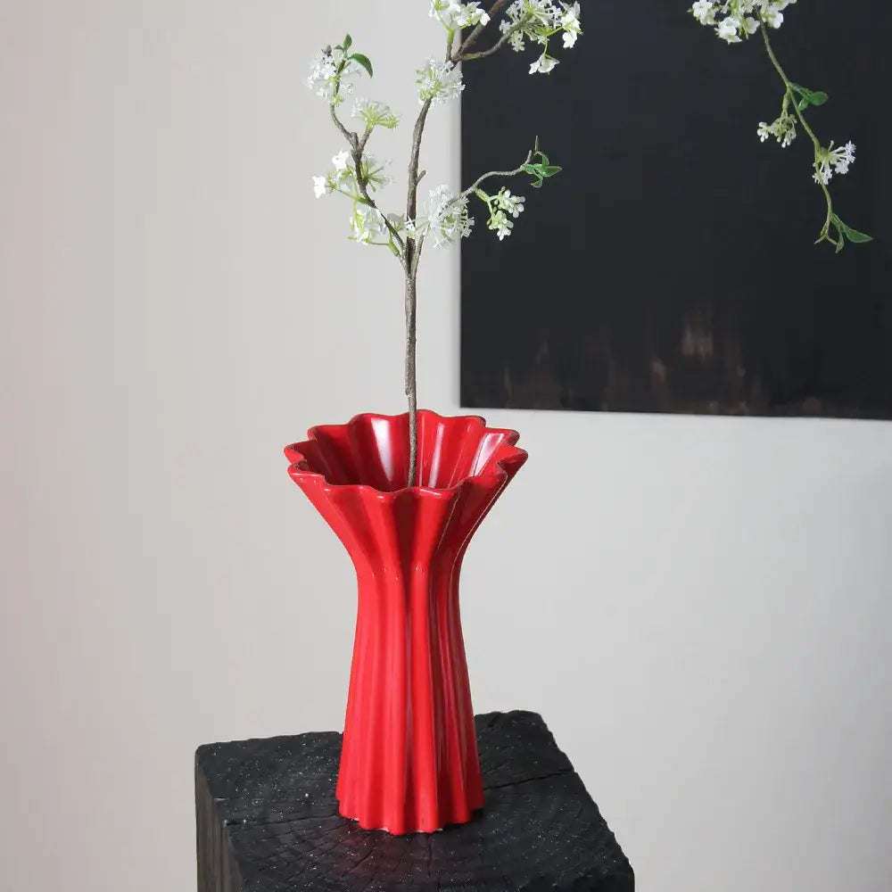 Vibrant red ceramic vase with geometric fold pattern and fluted petal-like rim featuring twine for living room decor