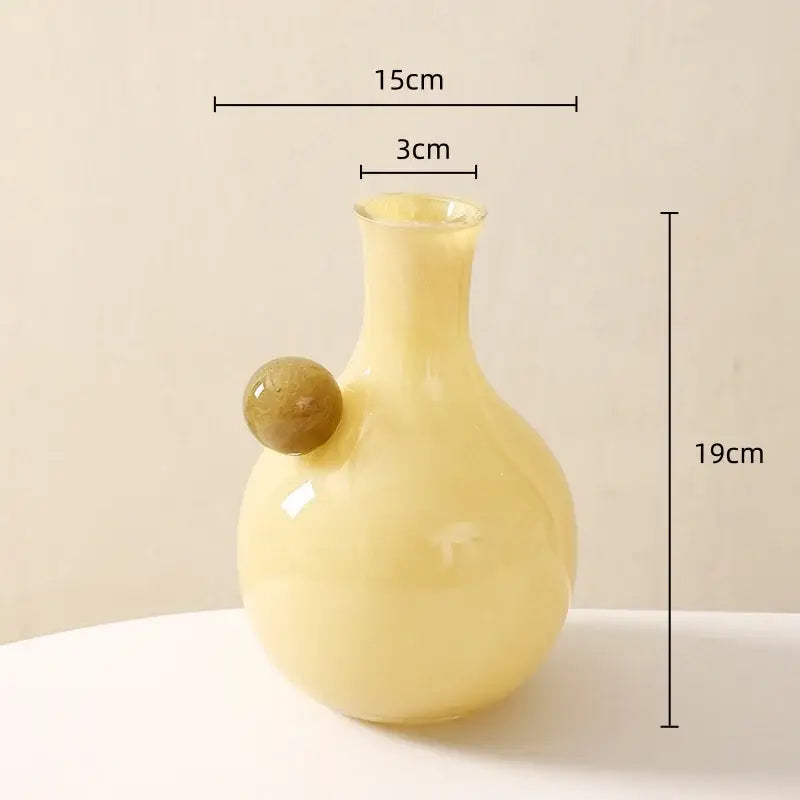 A pale yellow glossy glass sphere vase with an amber geometric glass sphere accent for decorbites geometric glass decor