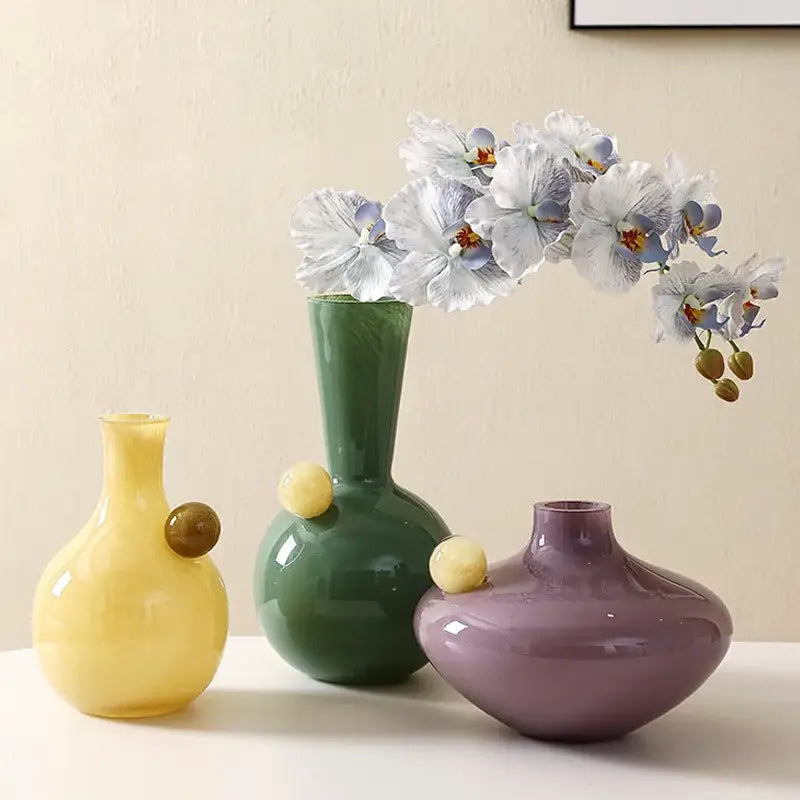 Three colorful glossy ceramic glass sphere vases in yellow green and purple with decorative accents for decorbites geometric glass sphere decor