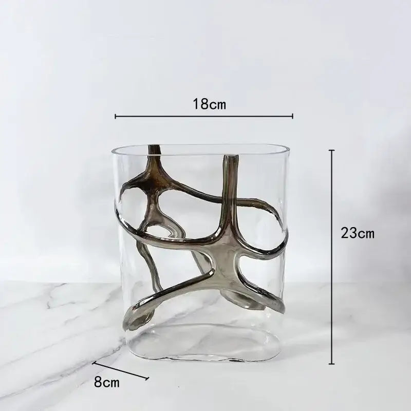 Clear glass vase with sleek silver abstract metallic sculpture wrapped around decorbites gold-edged glass vase
