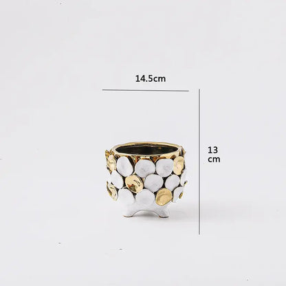 A small two-toned ceramic planter with geometric gold leaf relief featuring white and gold textured discs for decor