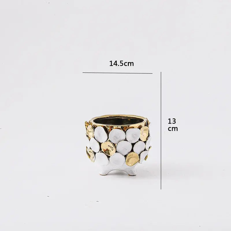 A small two-toned ceramic planter with geometric gold leaf relief featuring white and gold textured discs for decor