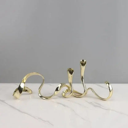 Gold-toned abstractly twisted metal geometric gold candlestick holder with sleek polished curves for dining room decor
