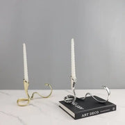 Two elegant geometric gold and silver candlestick holders with white textured taper candles for dining room decorbites centerpiece