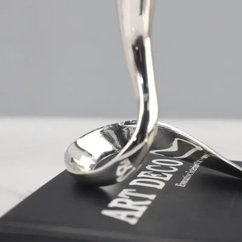 Shiny silver spoon-shaped sculpture as part of decorbites geometric gold and silver candlestick holder centerpiece