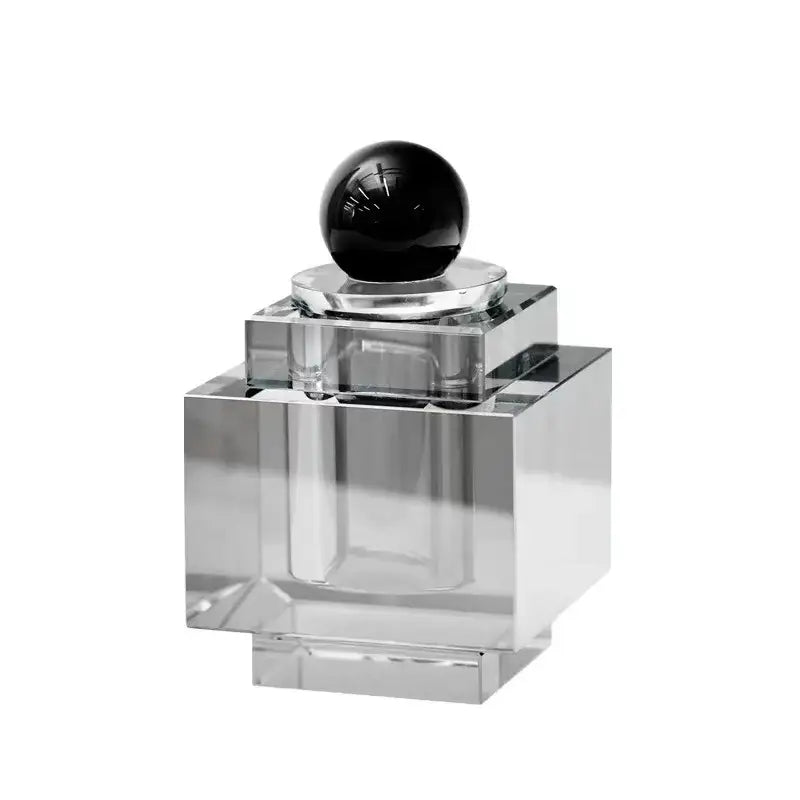 Clear acrylic perfume bottle with glossy black stopper displayed alongside geometric gold and silver crystal storage jar bedroom decor