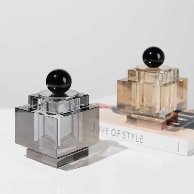 Two geometric crystal storage jars with gold and silver bases topped with black spherical caps for bedroom decor