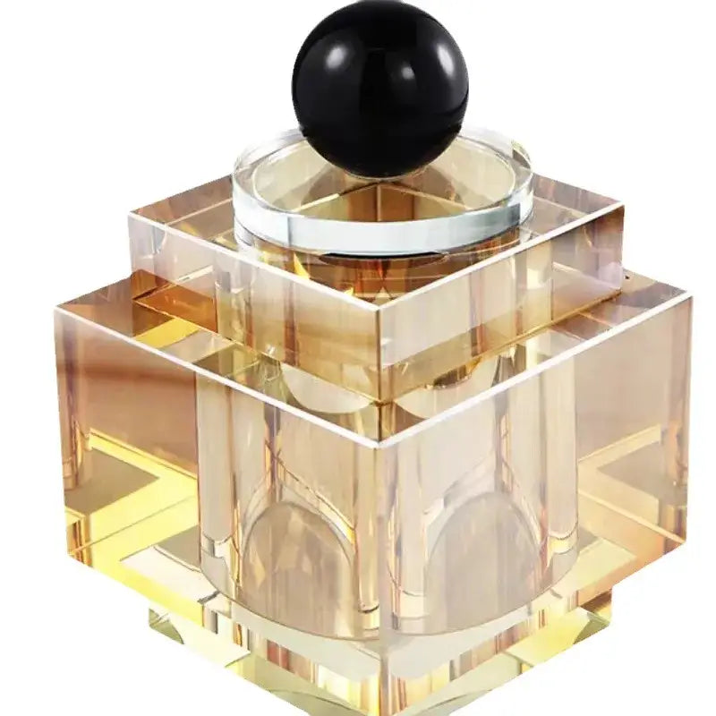 A sleek geometric storage jar with faceted amber glass and a glossy black stopper for bedroom jewelry storage
