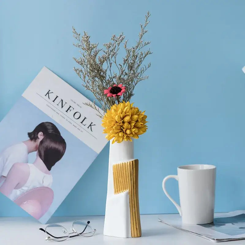 A modern white ceramic vase with a geometric gold striped design and textured panel holding dried flowers for living room hydroponics