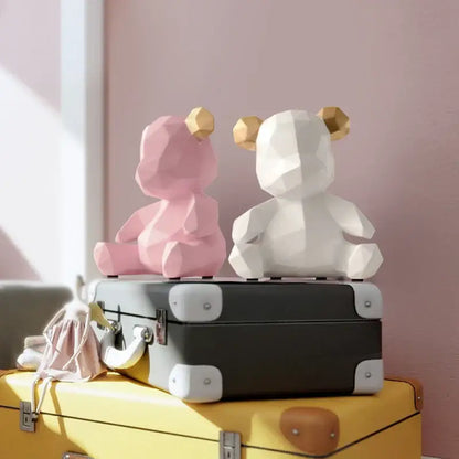 Two geometric bear figurines resin sculpture in pink and white with gold-tipped ears on vintage suitcase decor