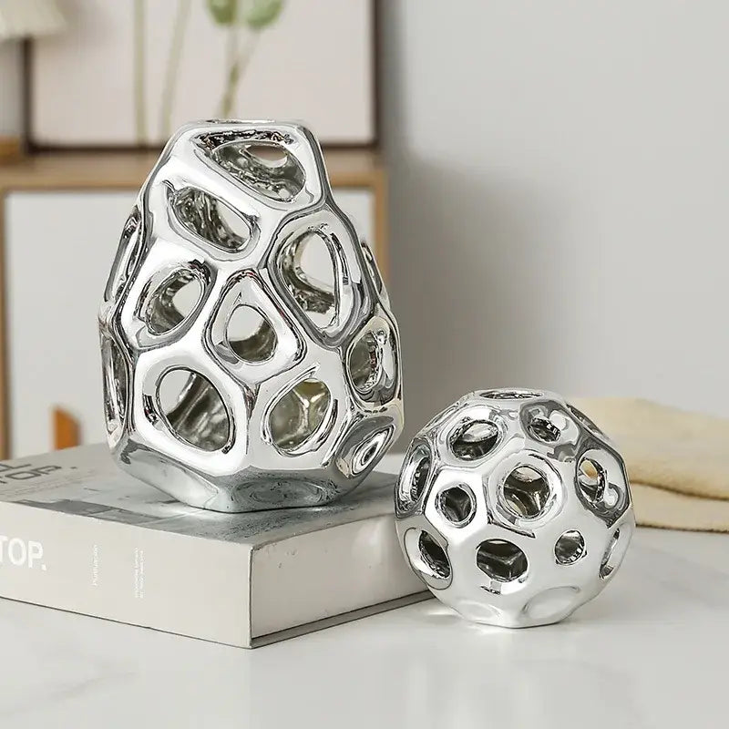 Shiny silver ceramic decorative orbs with intricate organic hole patterns for geometric golden hollow living room decor