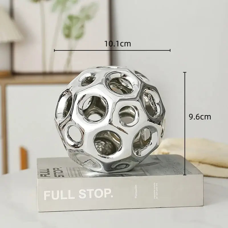 Shiny silver ceramic sphere with a geometric perforated design for decorbites geometric golden hollow living room decor