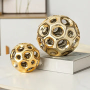 Two golden hollow ceramic spheres with geometric honeycomb circular cutouts for living room decorbites decor