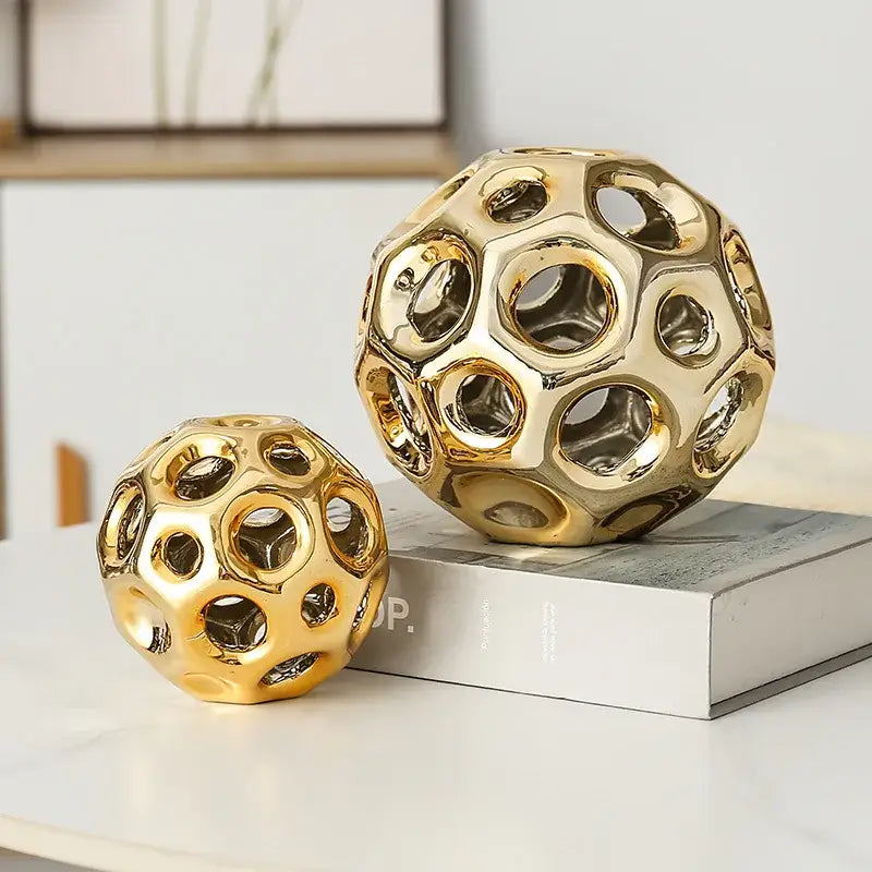 Two golden hollow ceramic spheres with geometric honeycomb circular cutouts for living room decorbites decor