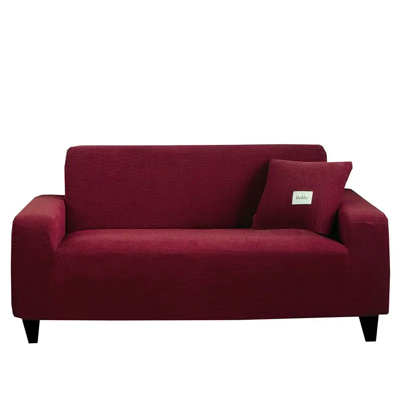 Deep red stretch couch cover with matching pillow and small white label complementing geometric gray textured sofa cover