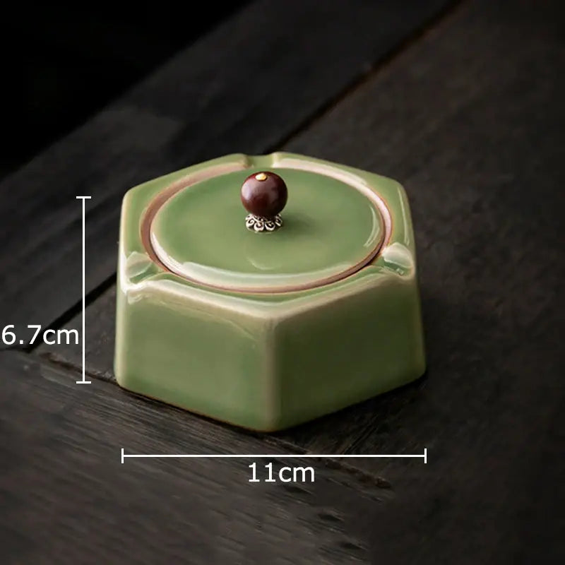 Geometric green ceramic ashtray with lid featuring a hexagonal shape and dark brown knob with silver detailing for office decorbites decor