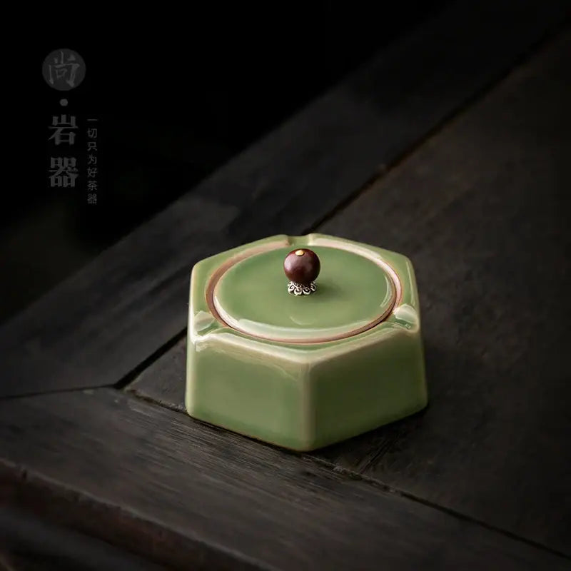 Geometric green ceramic ashtray with lid featuring a dark brown knob and silver detailing for office desk decorbites geometric green