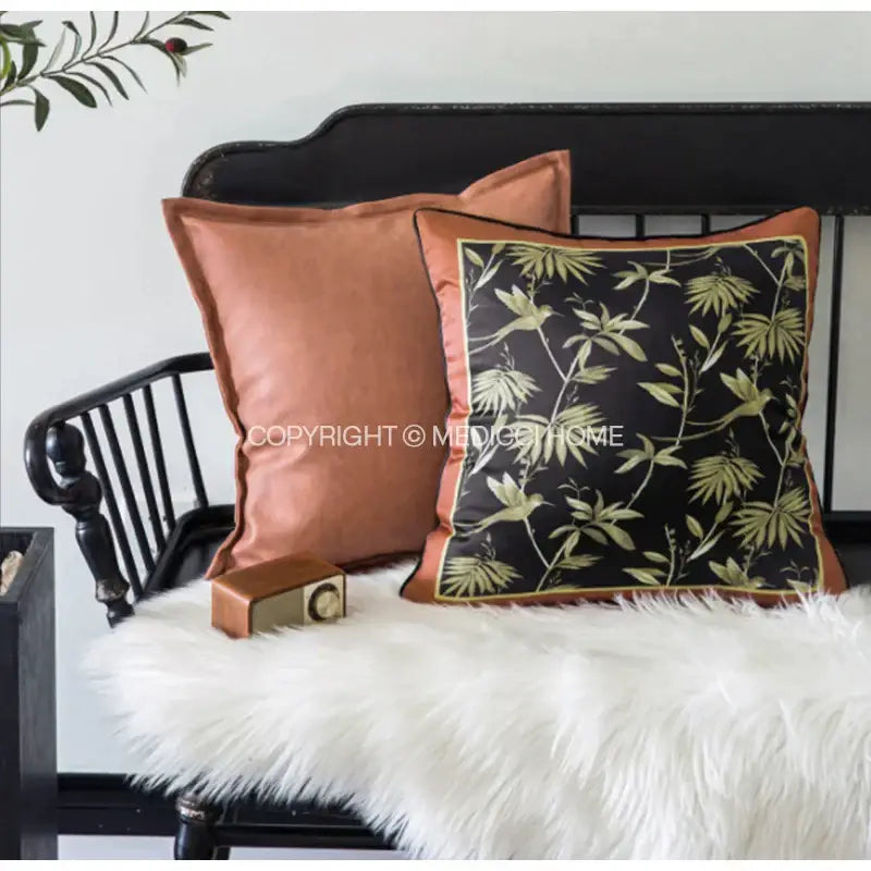 Black cushion with green leaf pattern and rust border complementing decorbites indigo blue and white embroidered pillow covers