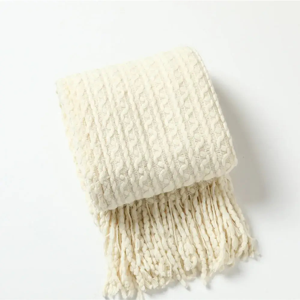 Cream-colored knitted scarf with textured cable pattern and fringe complementing decorbites geometric knit sofa blanket
