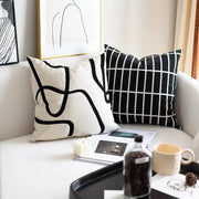 Two black and white geometric line embroidered suede throw pillows on a light sofa for modern living room decorbites decor