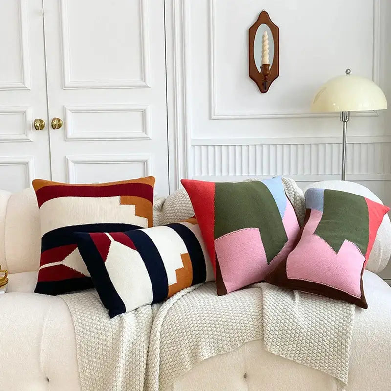 Three colorful geometric multi color knitted cushion cover set with bold stripes on a cream sofa for living room decor
