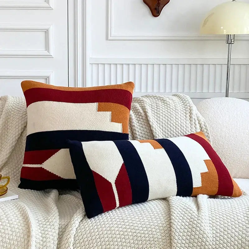 Two rectangular knit throw pillows with bold geometric stripes in cream rust orange navy blue and deep red cushion cover set