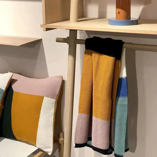 A vibrant multicolored decorbites knitted chenille scarf with bold geometric pattern in mustard yellow pink teal and black