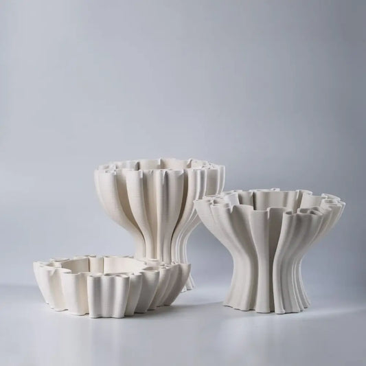 Three off-white ceramic flower pot sculptures with ruffled fluted sides and matching circular bases for living room decor