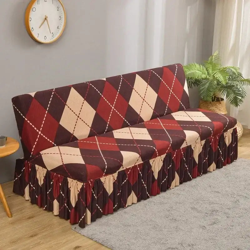 A cozy futon sofa covered with a stretchy argyle-patterned sofa cover in bold red and beige with white dotted lines