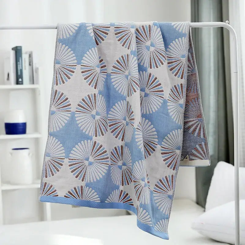A soft light blue and white cotton gauze bath towel with brown and white fan designs from decorbites cotton gauze set