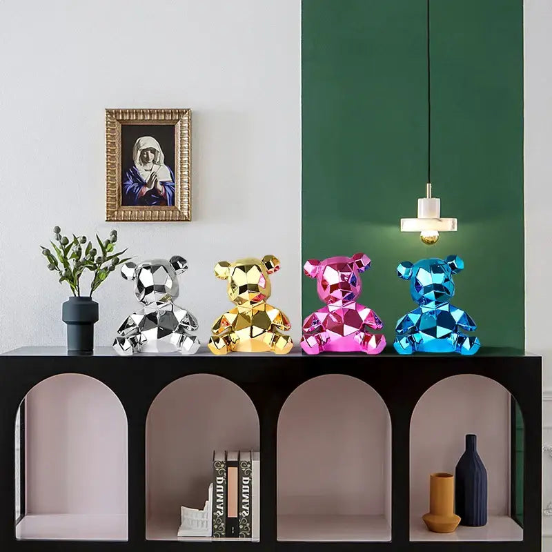 Four faceted electroplated teddy bear sculptures in silver gold pink and blue on a black console table for living room