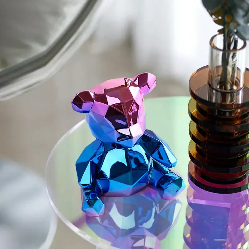 A vibrant electroplated teddy bear sculpture with a glossy blue and pink geometric finish for living room decor