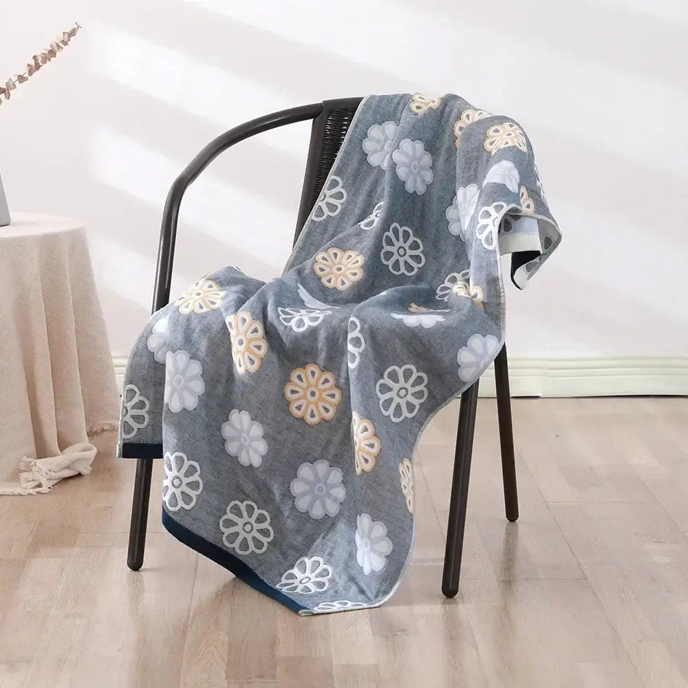 Gray decorbites cotton bath towel with white and beige embroidered flowers draped over dark metal chair